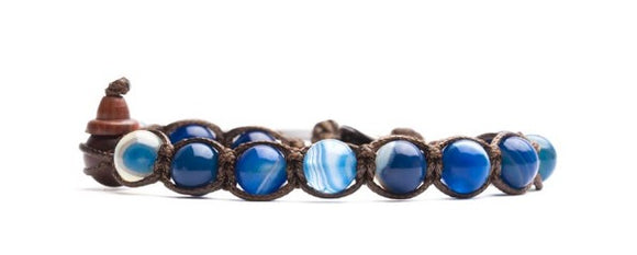 Bracciale originale tibetano Tamashii realizzato con pietre naturali AGATA BLU STRIATA. Misura pietre: 8mm. Unisex e taglia unica (il bracciale è predisposto per adattarsi a qualsiasi diametro di polso).  Ogni bracciale è spedito con relativa confezione originale e certificato di garanzia.