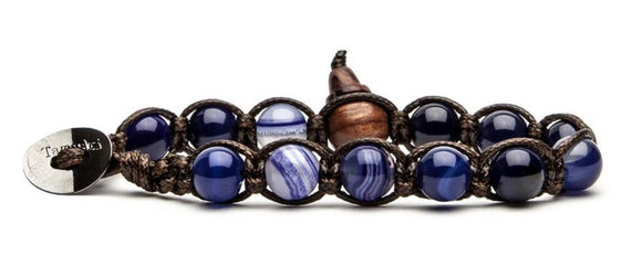 Bracciale originale tibetano Tamashii realizzato con pietre naturali AGATA BLU SCURO STRIATA. Misura pietre: 8mm. Unisex e taglia unica (il bracciale è predisposto per adattarsi a qualsiasi diametro di polso).  Ogni bracciale è spedito con relativa confezione originale e certificato di garanzia.